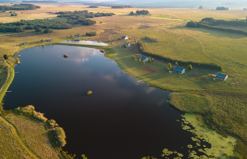 Aerial view of Blue Crane Farm in Dullstroom featuring luxury self-catering cottages beside a tranquil trout fishing dam